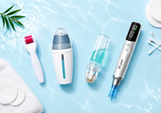 Flat lay of microneedling skincare tools, including a Dr. Pen microneedling pen, derma roller, derma stamp and serum applicator, arranged with cotton pads, cotton swabs and green leaves on a clean white and light blue background.