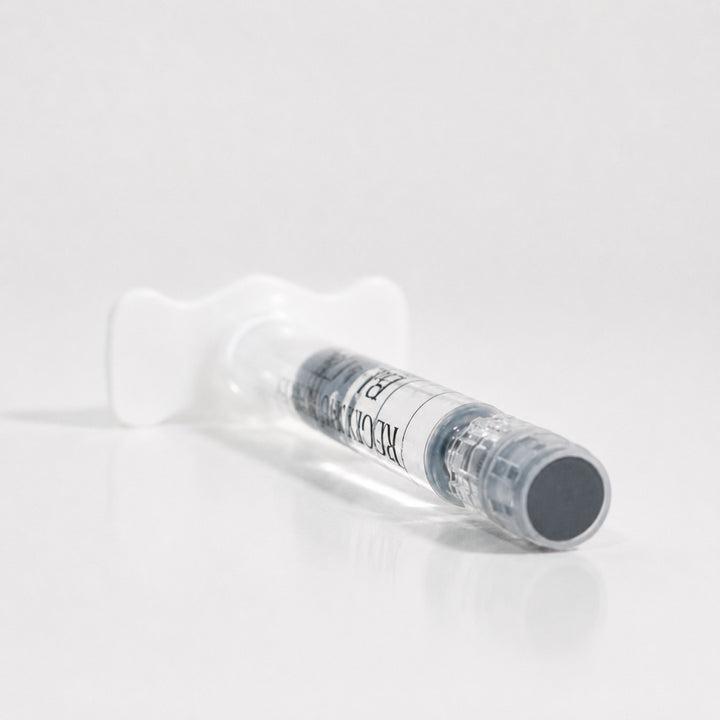 Close-up of Reglory Eyes Black PN 1% syringe lying on a white reflective surface