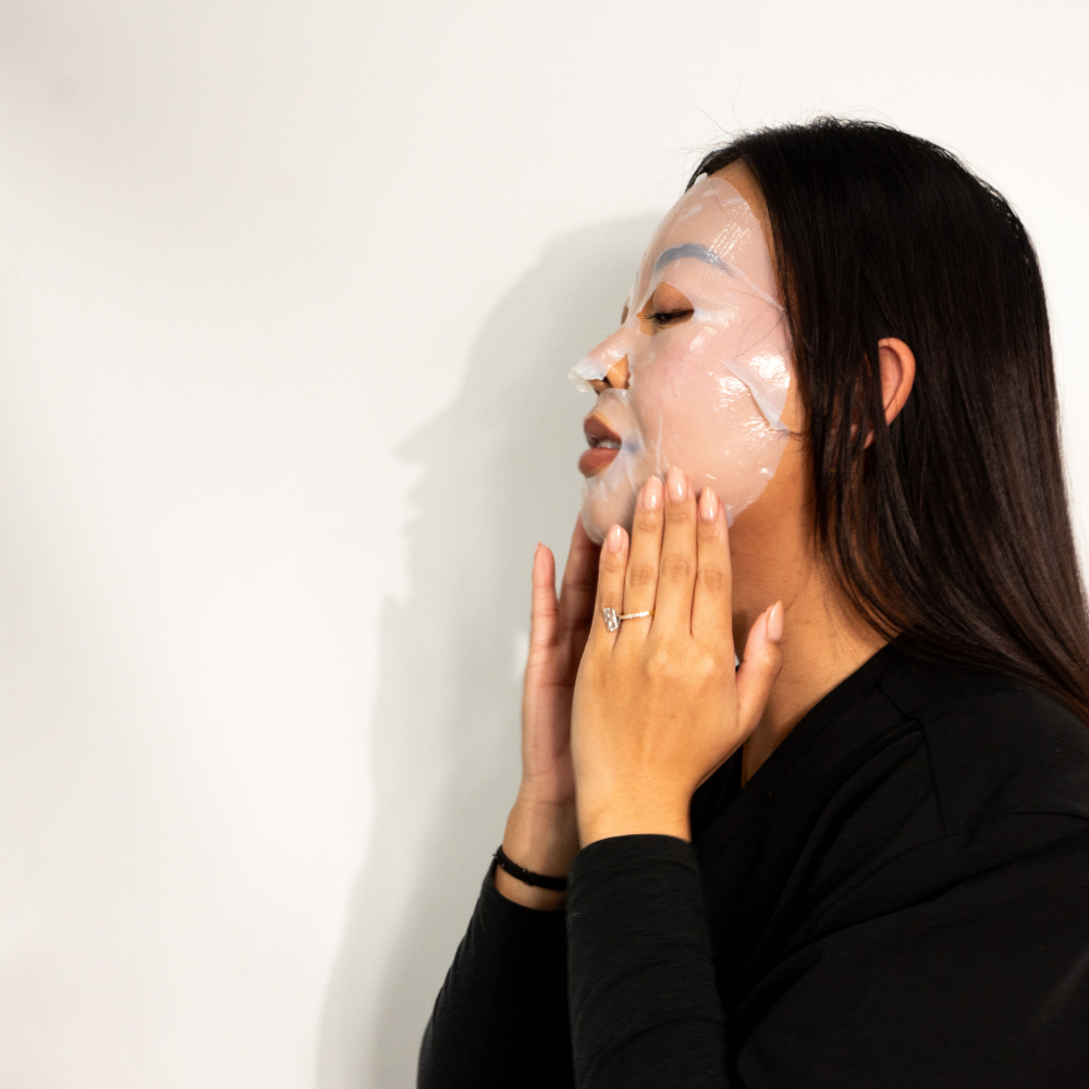 Side view of woman smoothing on Dr. Pen x Peachaboo Hydra Repair Biocellulose Post-Treatment Recovery Mask, a soothing and hydrating face mask for rejuvenated skin.